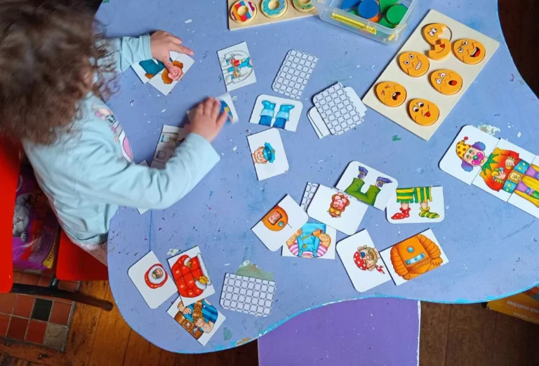 A child plays a matching game with picture cards spread across a blue table.