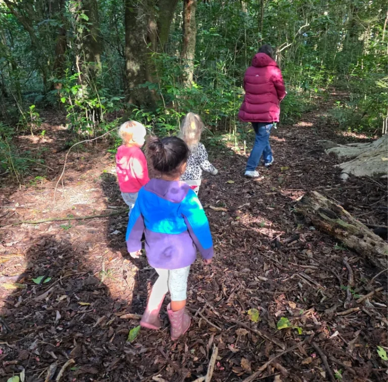 Young children walk along a leafy bush track.