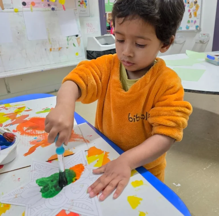 A boy paints with a pipette onto a star-shaped paper.