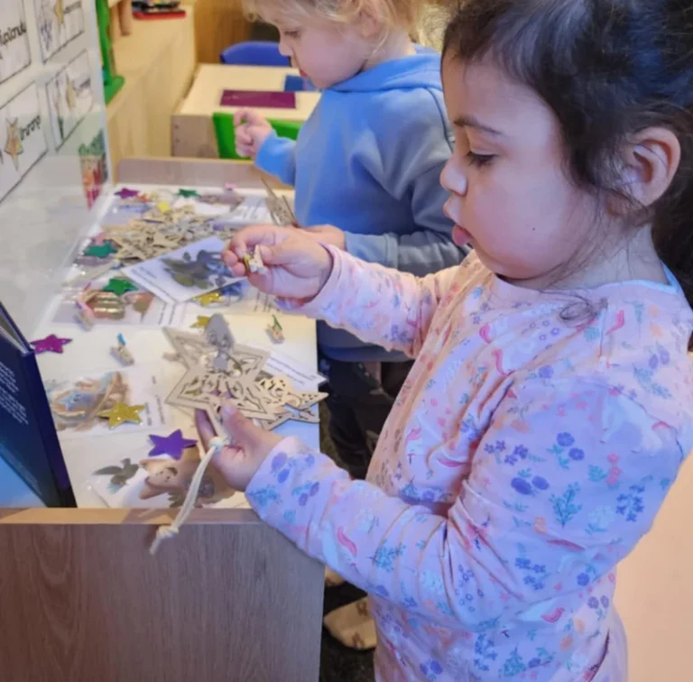 A girl decorates a star craft with sequins.