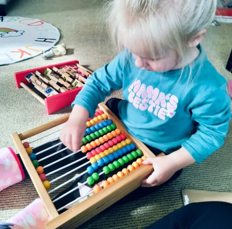 A toddler moves beads on a wooden abacus.