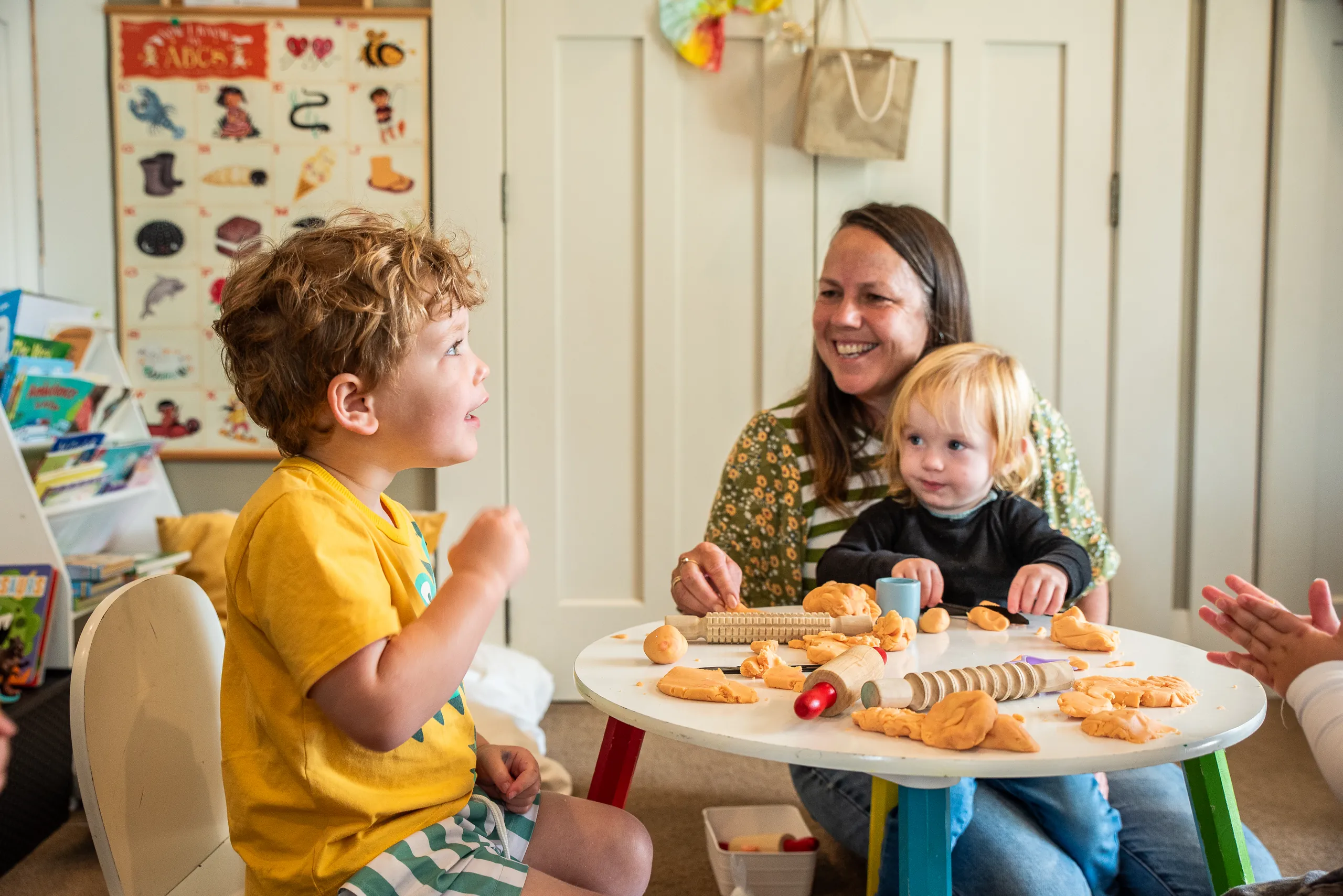An Educator and two children sharing a playdough activity at a small round table